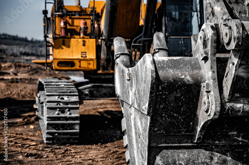 Yellow excavator steel bucket working on construction open mining site