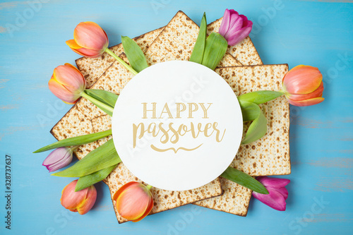 Jewish holiday Passover greeting card with matzah and tulip flowers on wooden table. Pesach background.