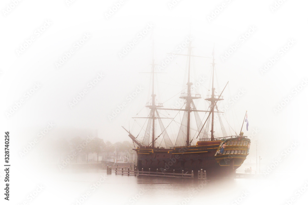 Old wooden dutch galeon in harbour. High key image of vintage battleship in a fog.