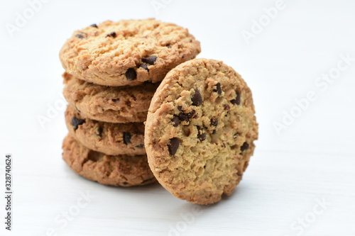 Oatmeal cookies and chocolate chips on light background