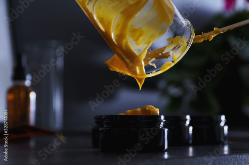 Fresh diy natural skincare sream dropping into black glass jar