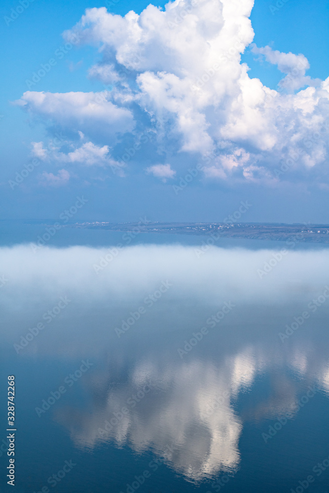 fog above the lake, clouds at sky and its reflection in the water