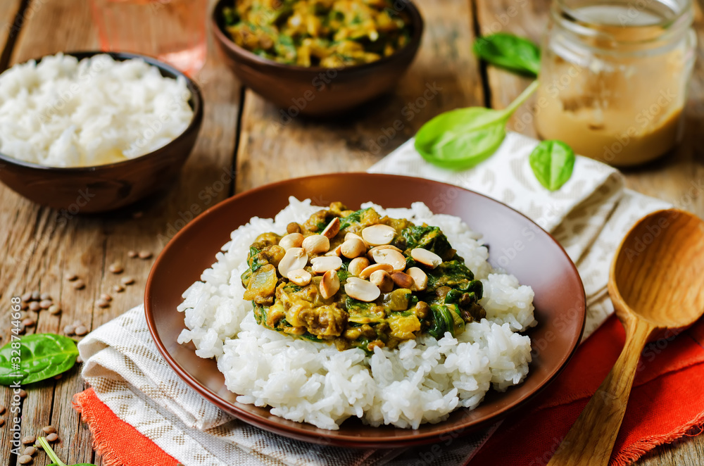 lentils, peanut butter spinach curry with rice on a wood background lentils, peanut butter spinach curry with rice on a wood background