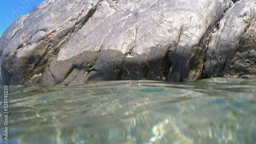 Part of a big smooth rock filmed both above sea level  and submerged  