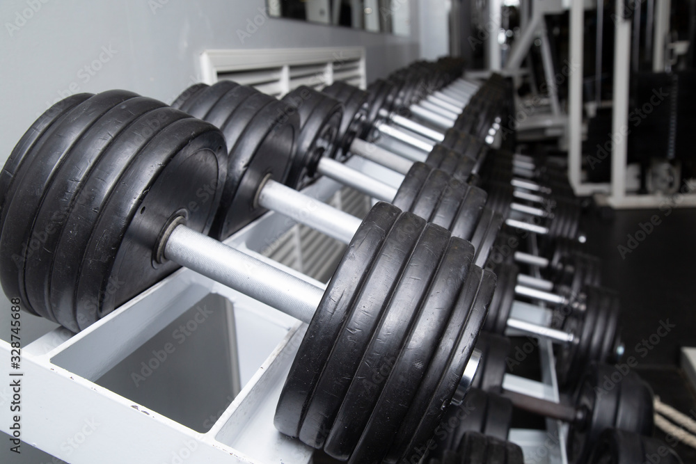 Black dumbbells for fitness classes in the gym.