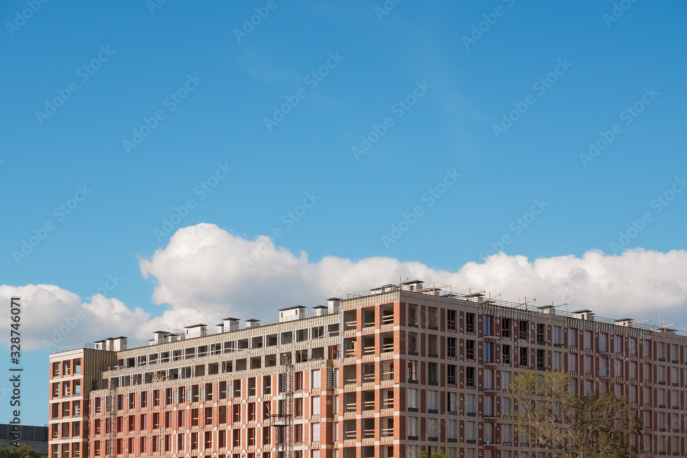 New building construction. construction of an apartment building against blue sky. new luxury district of town. promising development of the city . Facing the building with bricks