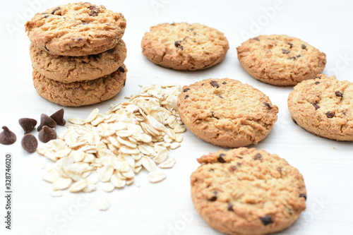 Oatmeal cookies and chocolate chips on light background