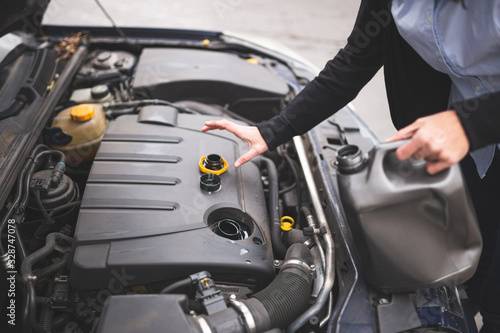 Young Caucasian woman checking the car's engine oil. Car maintenance concept.