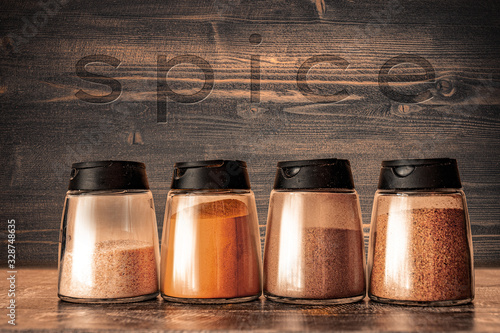 Fototapeta Naklejka Na Ścianę i Meble -  Cooking base kitchen concept - Set of spice shakers - Powder spices in jars on wooden desk 
