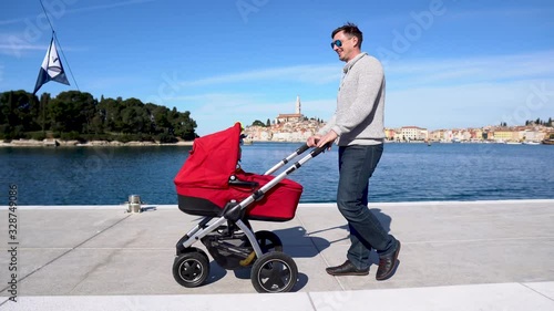 A man with a baby strolley walking by the sea photo