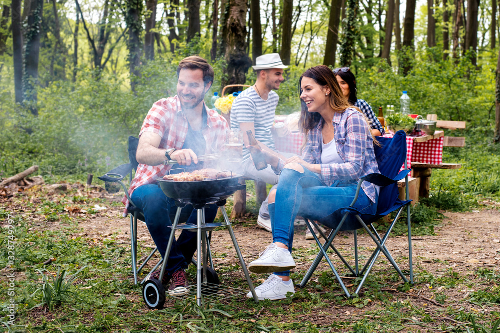 Friends hanging out having fun while making barbecue in nature Friends hanging out having fun while making barbecue in nature