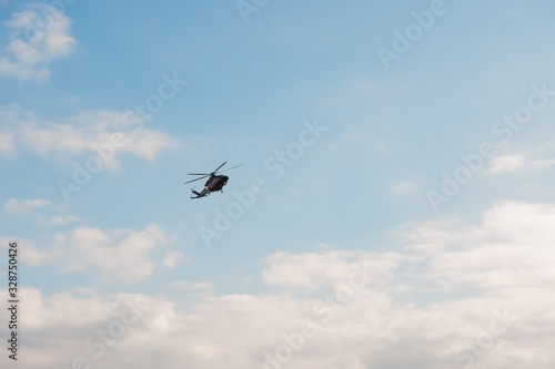 Modern helicopter flying in the blue sky.Flying transport helicopter.The aircraft, the black helicopter at competitions makes flight at low height.