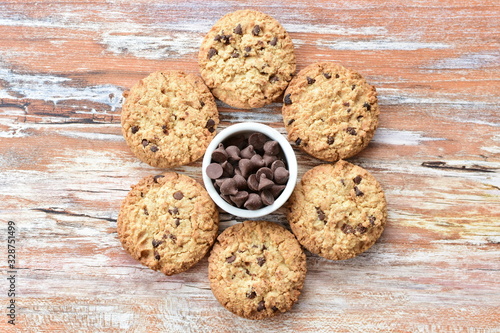 Oatmeal cookies and chocolate chips on light background