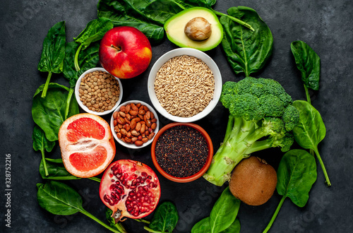 Selection of healthy food: fruits, seeds, cereals, superfoods, vegetables, leafy vegetables on a stone background. Healthy food for humans.