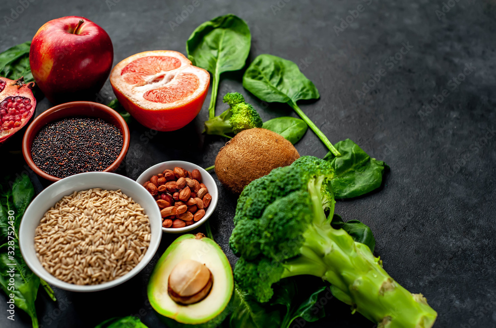 Selection of healthy food: fruits, seeds, cereals, superfoods, vegetables, leafy vegetables on a stone background. Healthy food for humans. Copy space for your text. Selection of healthy food: fruits, seeds, cereals, superfoods, vegetables, leafy vegetables on a stone background. Healthy food for humans. Copy space for your text.