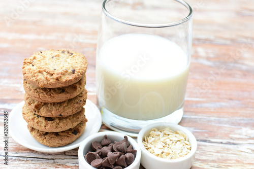 Oatmeal cookies and chocolate chips accompanied by glass of milk