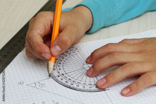 Closeup child's hands measuring angle by protractor