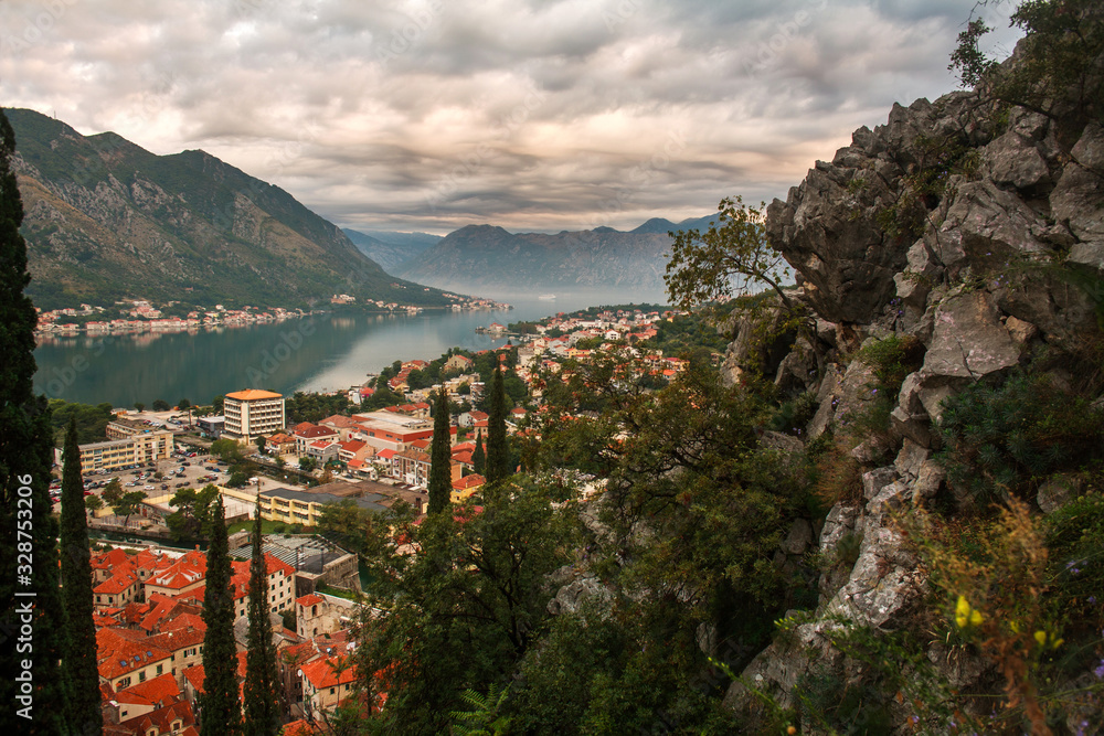 Tops of roofs of the old city of Kotor on background of bay, mountains and sky