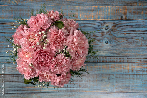 Pink carnation flowers bucket on blue wooden background.