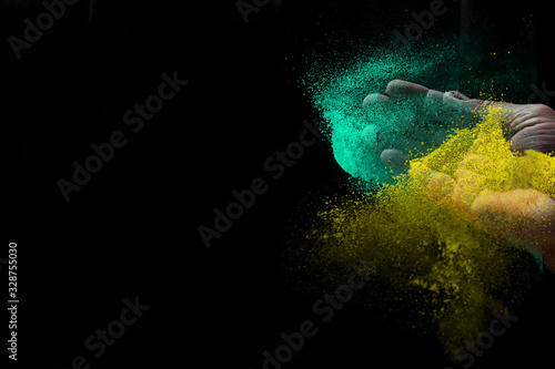 Indian woman hand colourful holi powder splash at black background, Holi celebration
