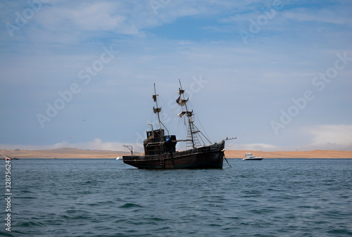 an old black pirate ship wrecked in the middle of the ocean and in the background a desert