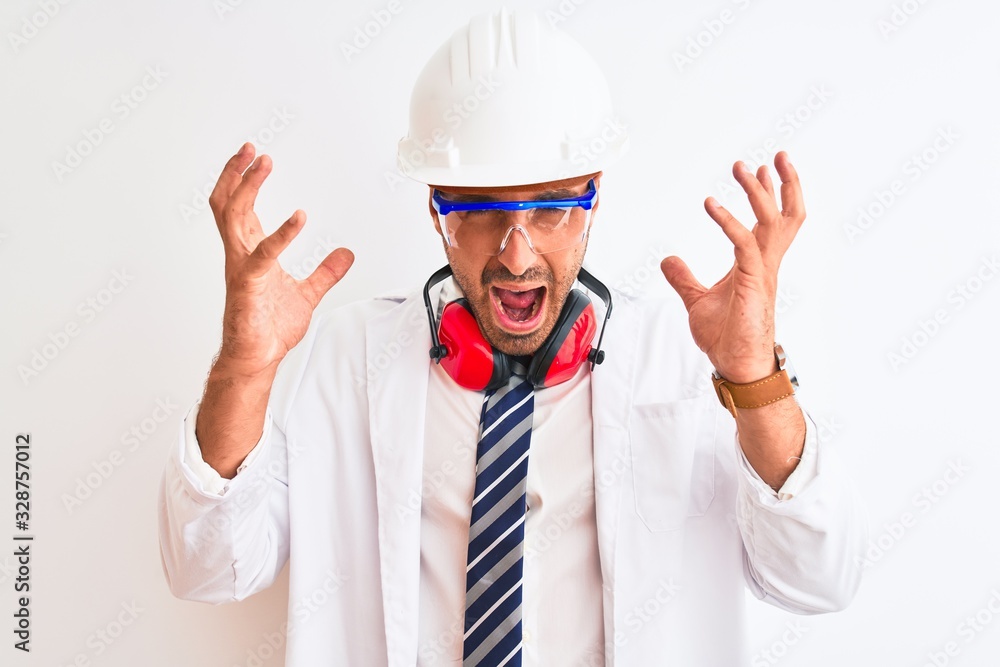 Young chemist man wearing security helmet and headphones over isolated background celebrating mad and crazy for success with arms raised and closed eyes screaming excited. Winner concept Young chemist man wearing security helmet and headphones over isolated background celebrating mad and crazy for success with arms raised and closed eyes screaming excited. Winner concept
