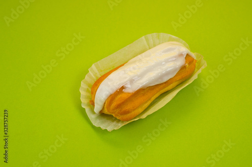 Eclair cake with custard lying on a paper substrate, photographed against a green background. Background for cooking and sweets.