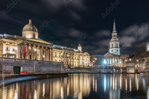 The National Gallery and St Martin-in-the-Fields church in London, night view over Trafalgar square fountains