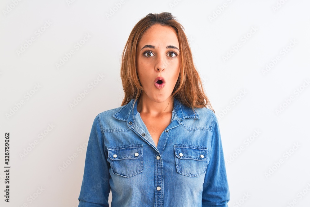 Young redhead woman wearing denim jacket standing over isolated background afraid and shocked with surprise expression, fear and excited face. Young redhead woman wearing denim jacket standing over isolated background afraid and shocked with surprise expression, fear and excited face.