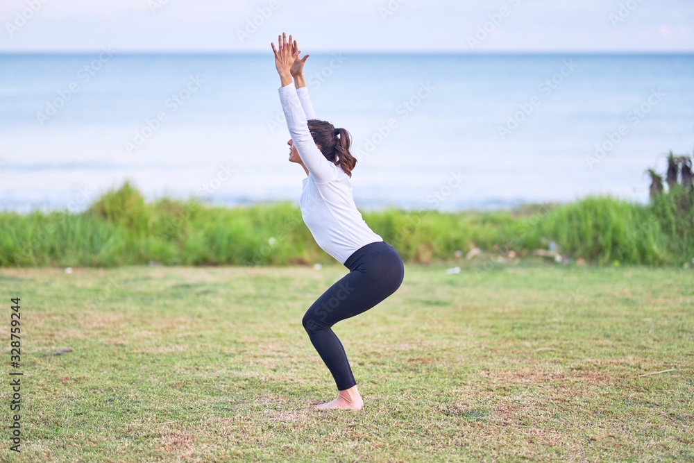 Young beautiful sportwoman practicing yoga. Coach teaching chair pose at park Young beautiful sportwoman practicing yoga. Coach teaching chair pose at park