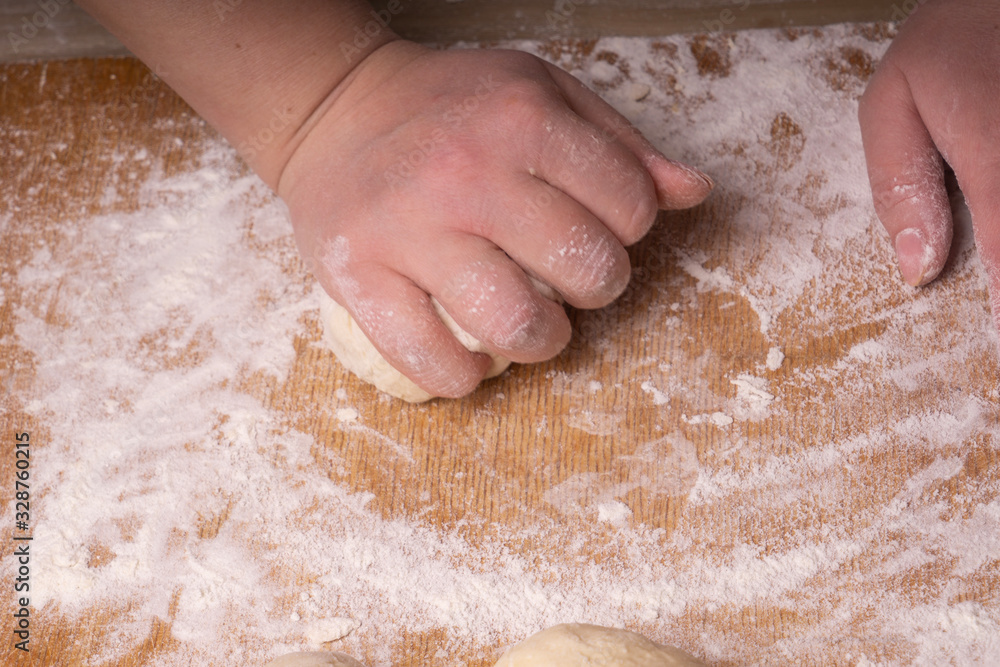 A woman kneads the dough. Plywood cutting board, wooden flour sieve and wooden rolling pin - tools for making dough. A woman kneads the dough. Plywood cutting board, wooden flour sieve and wooden rolling pin - tools for making dough.