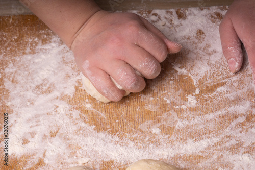 A woman kneads the dough. Plywood cutting board, wooden flour sieve and wooden rolling pin - tools for making dough.