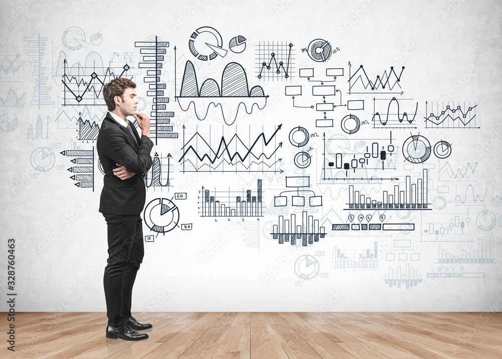 Pensive businessman looking at graphs on wall Pensive businessman looking at graphs on wall