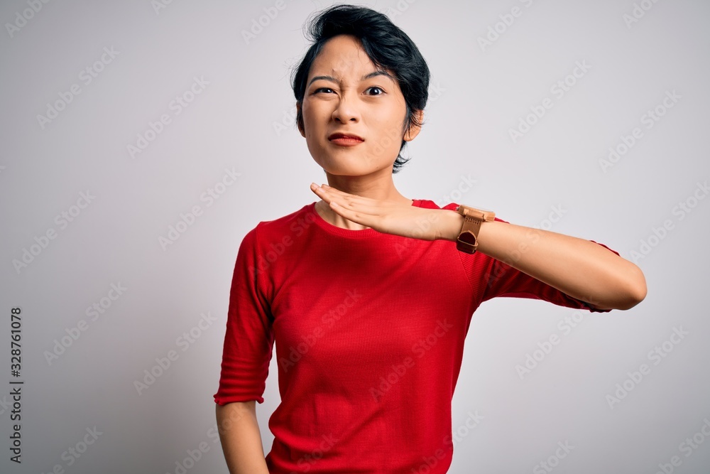 Young beautiful asian girl wearing casual red t-shirt standing over isolated white background cutting throat with hand as knife, threaten aggression with furious violence Young beautiful asian girl wearing casual red t-shirt standing over isolated white background cutting throat with hand as knife, threaten aggression with furious violence