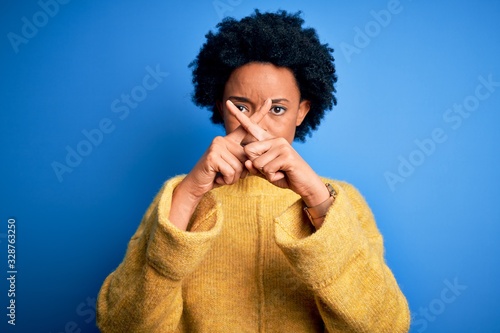 Young beautiful African American afro woman with curly hair wearing yellow casual sweater Rejection expression crossing fingers doing negative sign