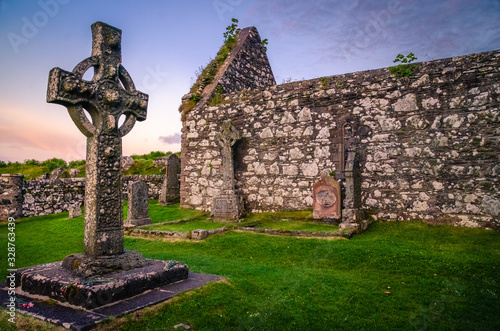 Stone religious celtic Kildalton cross on a cemetary beside a church on Islay island during sunset, Hebrides, West Scotland photo