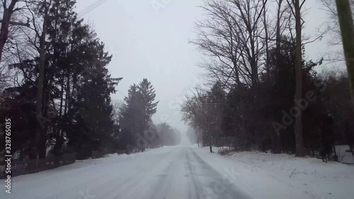 *Reverse Motion* Driving Winter Snow Storm Backward in Residential Suburb in Day.  Driver Point of View POV Snowing Blizzard Snowfall on Suburban Road.