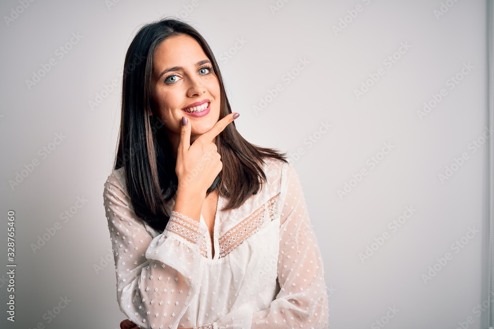 Young brunette woman with blue eyes wearing casual t-shirt over isolated white background looking confident at the camera smiling with crossed arms and hand raised on chin. Thinking positive. Young brunette woman with blue eyes wearing casual t-shirt over isolated white background looking confident at the camera smiling with crossed arms and hand raised on chin. Thinking positive.