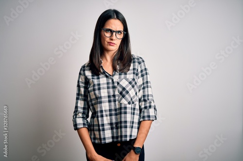Young brunette woman with blue eyes wearing casual shirt and glasses over white background skeptic and nervous, frowning upset because of problem. Negative person. © Krakenimages.com