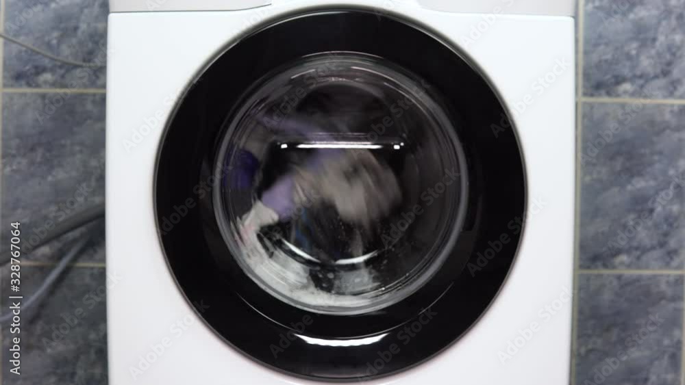 The washing machine is working. A washing machine spins a drum filled with clothes. The washing machine is working. A washing machine spins a drum filled with clothes.
