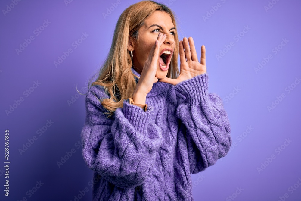 Young beautiful blonde woman wearing casual turtleneck sweater over purple background Shouting angry out loud with hands over mouth Young beautiful blonde woman wearing casual turtleneck sweater over purple background Shouting angry out loud with hands over mouth