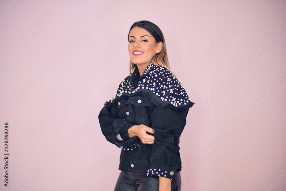 Young beautiful woman wearing fashionable clothes smiling happy and confident. Standing with smile on face over isolated pink background Young beautiful woman wearing fashionable clothes smiling happy and confident. Standing with smile on face over isolated pink background