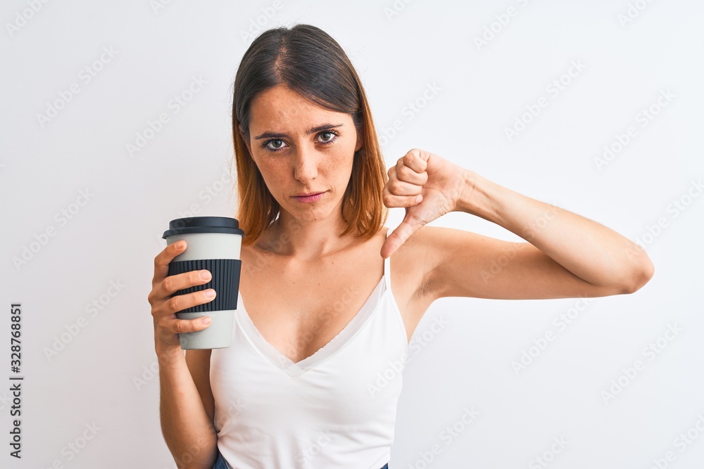 Beautiful redhead woman drinking take away coffee over isolated background with angry face, negative sign showing dislike with thumbs down, rejection concept Beautiful redhead woman drinking take away coffee over isolated background with angry face, negative sign showing dislike with thumbs down, rejection concept