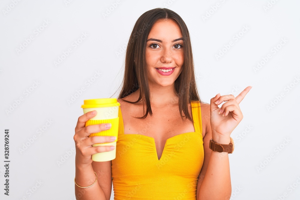 Young beautiful girl drinking paper glass of take away coffee over isolated white background very happy pointing with hand and finger to the side Young beautiful girl drinking paper glass of take away coffee over isolated white background very happy pointing with hand and finger to the side