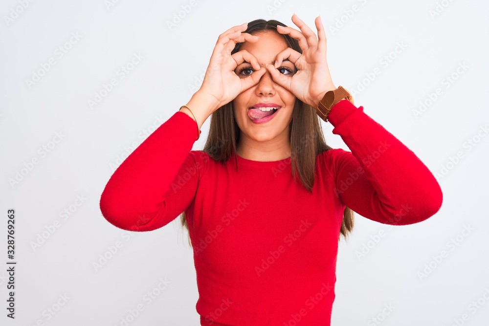 Young beautiful girl wearing red casual t-shirt standing over isolated white background doing ok gesture like binoculars sticking tongue out, eyes looking through fingers. Crazy expression. Young beautiful girl wearing red casual t-shirt standing over isolated white background doing ok gesture like binoculars sticking tongue out, eyes looking through fingers. Crazy expression.
