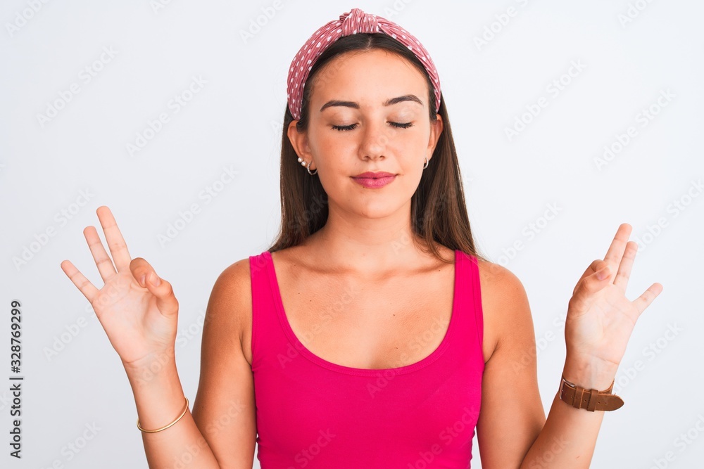 Young beautiful girl wearing pink casual t-shirt and diadem over isolated white background relax and smiling with eyes closed doing meditation gesture with fingers. Yoga concept. Young beautiful girl wearing pink casual t-shirt and diadem over isolated white background relax and smiling with eyes closed doing meditation gesture with fingers. Yoga concept.