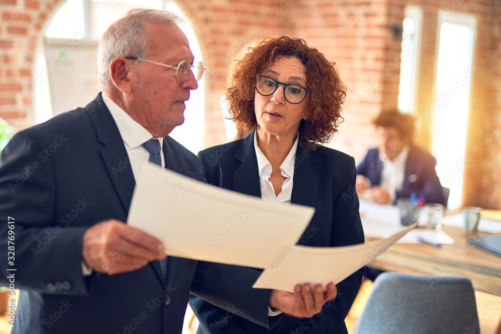 Two business workers working together. Speaking and reading documents standing at the office Two business workers working together. Speaking and reading documents standing at the office