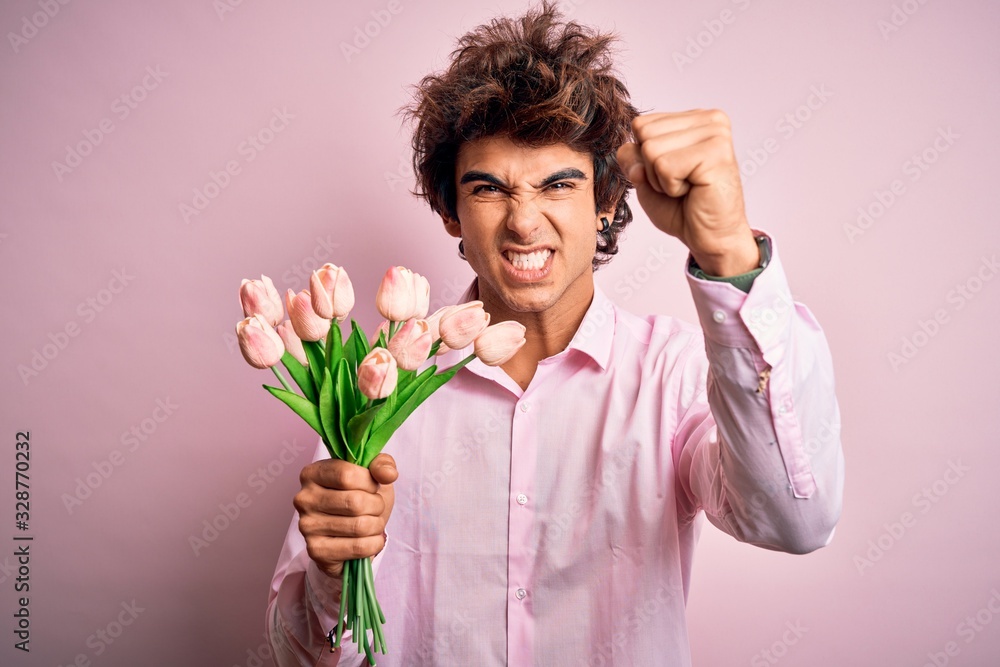 Young handsome man holding flowers standing over isolated pink background annoyed and frustrated shouting with anger, crazy and yelling with raised hand, anger concept Young handsome man holding flowers standing over isolated pink background annoyed and frustrated shouting with anger, crazy and yelling with raised hand, anger concept