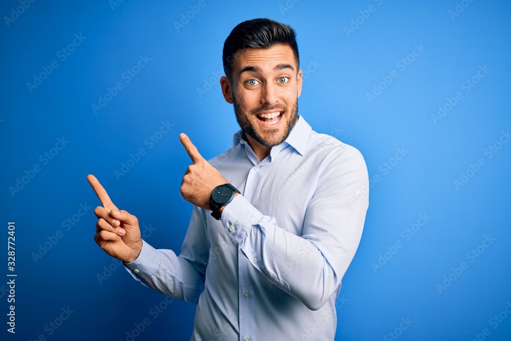 Young handsome man wearing elegant shirt standing over isolated blue background smiling and looking at the camera pointing with two hands and fingers to the side. Young handsome man wearing elegant shirt standing over isolated blue background smiling and looking at the camera pointing with two hands and fingers to the side.