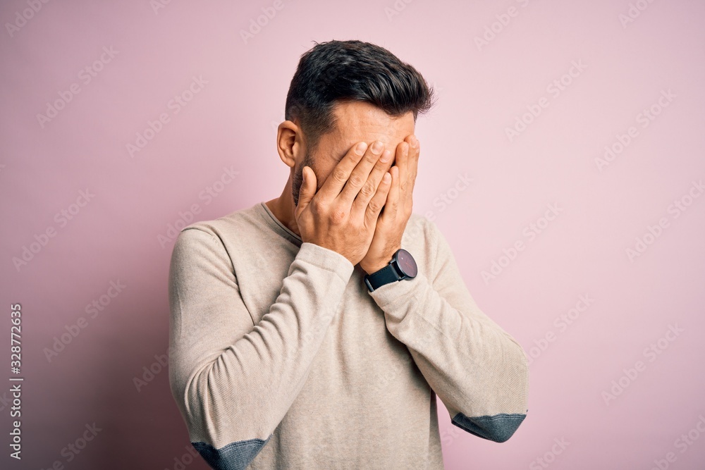 Young handsome man wearing casual sweater standing over isolated pink background with sad expression covering face with hands while crying. Depression concept. Young handsome man wearing casual sweater standing over isolated pink background with sad expression covering face with hands while crying. Depression concept.